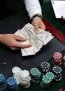 Close-up of hands counting dollar bills on a casino table with poker chips.